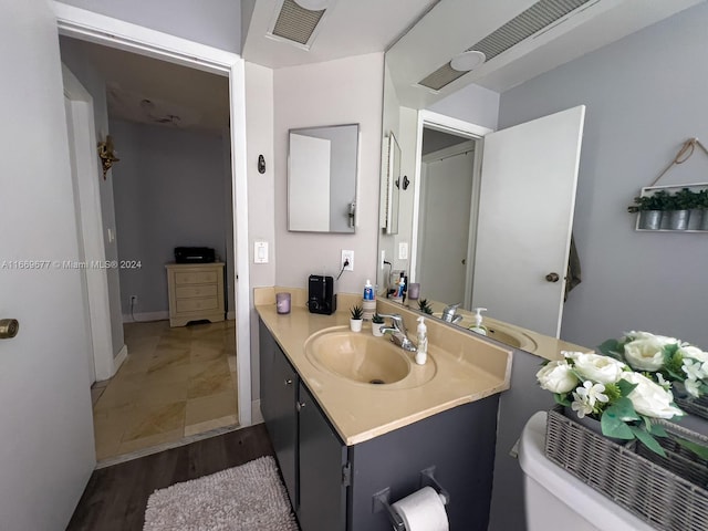 bathroom with wood-type flooring, vanity, and toilet