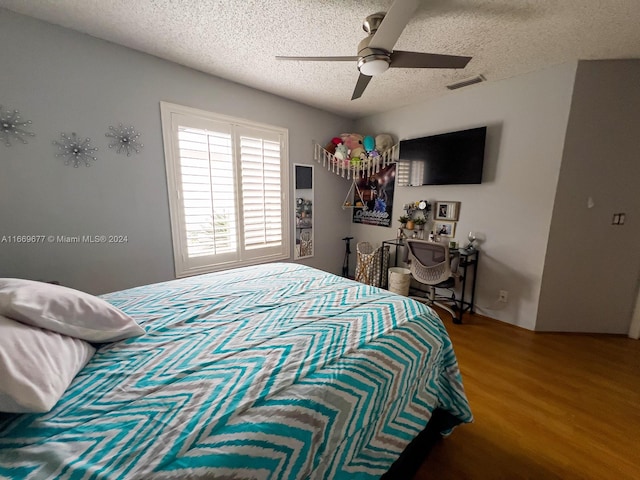 bedroom with ceiling fan, a textured ceiling, and hardwood / wood-style floors