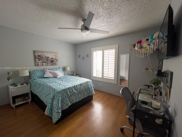 bedroom with ceiling fan, a textured ceiling, and hardwood / wood-style floors