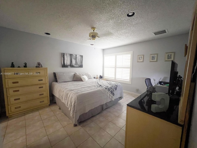 bedroom featuring a textured ceiling, light tile patterned floors, and ceiling fan