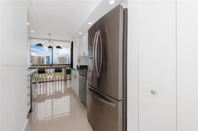 kitchen with pendant lighting, stainless steel appliances, white cabinets, and light tile patterned flooring