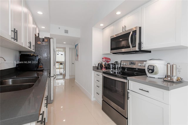 kitchen featuring white cabinets, light tile patterned flooring, stainless steel appliances, and sink