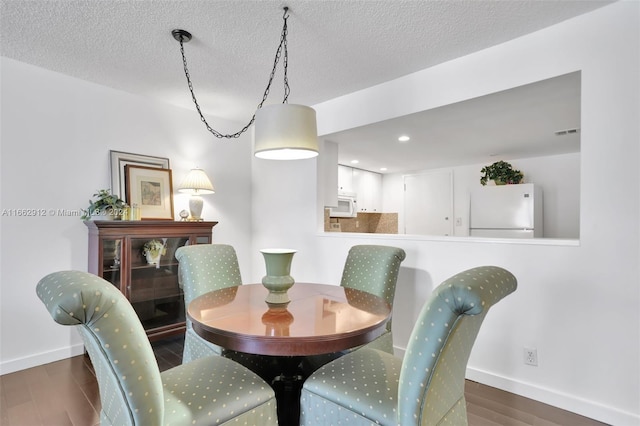 dining area featuring a textured ceiling and dark wood-type flooring