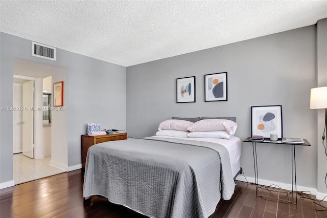 bedroom featuring a textured ceiling and dark hardwood / wood-style floors