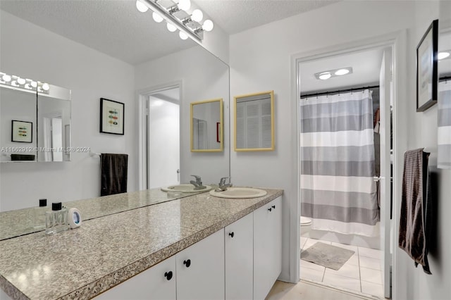 bathroom with vanity, toilet, curtained shower, a textured ceiling, and tile patterned flooring