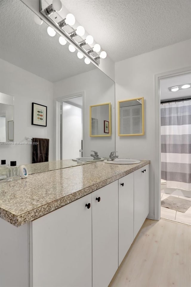 bathroom with vanity, toilet, a textured ceiling, and hardwood / wood-style flooring