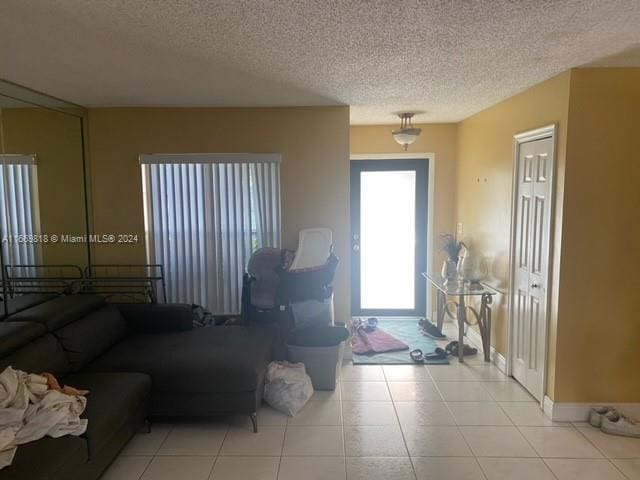 unfurnished living room featuring a textured ceiling and light tile patterned flooring