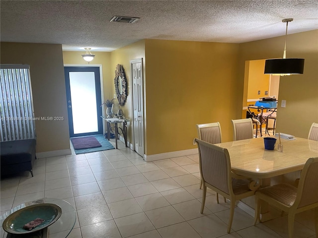 dining room featuring visible vents, light tile patterned flooring, a textured ceiling, and baseboards