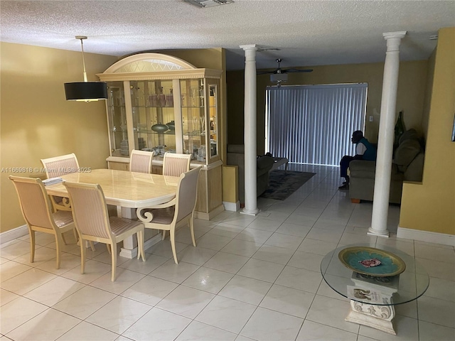 dining space featuring a textured ceiling, light tile patterned flooring, and decorative columns