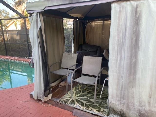 view of patio / terrace with a fenced in pool, glass enclosure, fence, and a gazebo