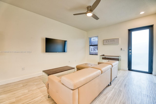 living room with light hardwood / wood-style flooring, ceiling fan, and a textured ceiling