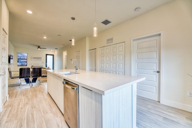 kitchen with pendant lighting, dishwasher, light hardwood / wood-style floors, sink, and a center island with sink