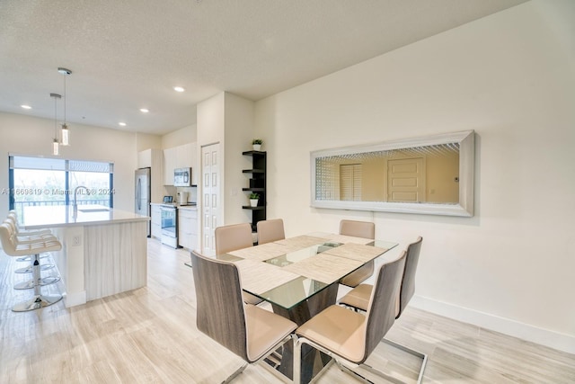 dining space with light hardwood / wood-style flooring, a textured ceiling, and sink