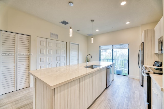 kitchen with a center island with sink, appliances with stainless steel finishes, decorative light fixtures, and sink