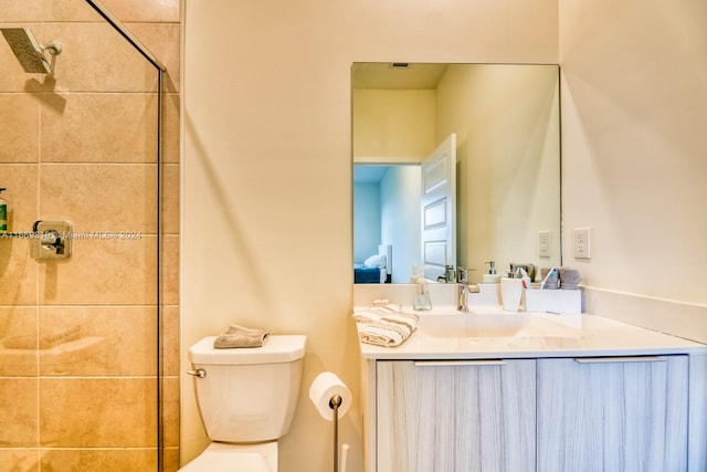 bathroom with vanity, toilet, and tiled shower