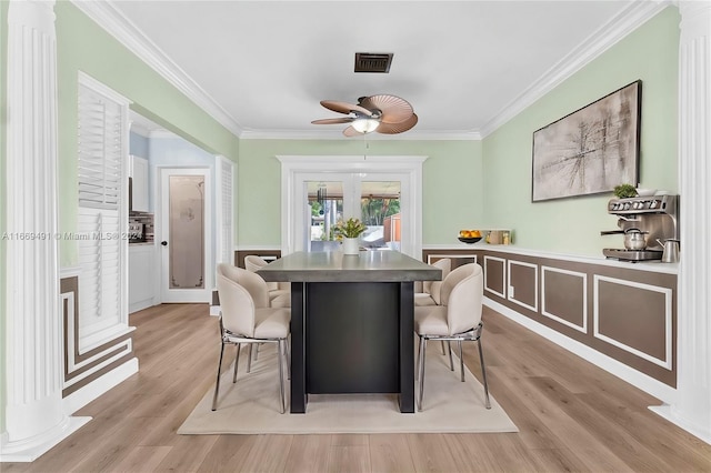 dining space with ceiling fan, light wood-type flooring, decorative columns, and ornamental molding