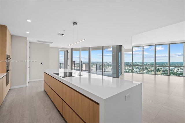 kitchen featuring pendant lighting, black electric stovetop, double oven, a spacious island, and expansive windows