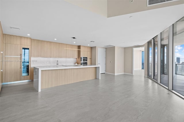 kitchen featuring light brown cabinets, backsplash, pendant lighting, and a center island