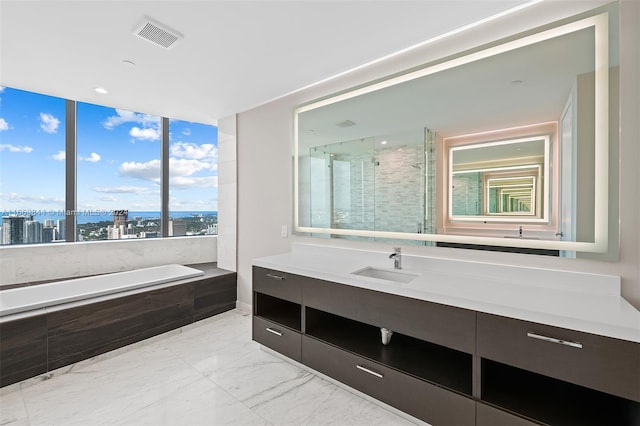 bathroom featuring independent shower and bath, vanity, and a wealth of natural light