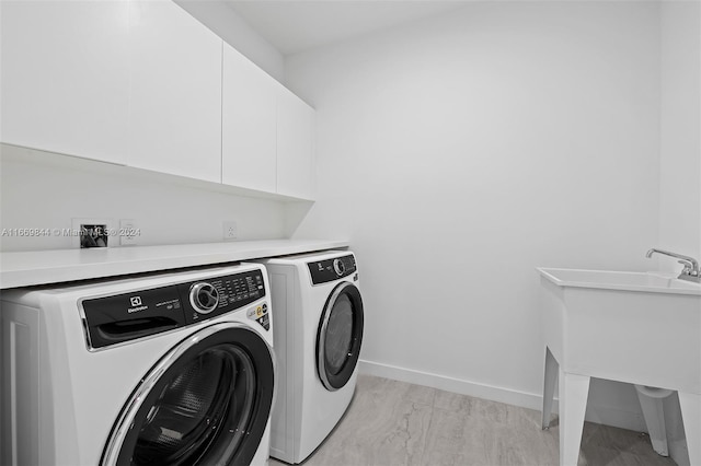 laundry area featuring cabinets, light wood-type flooring, and washer and clothes dryer