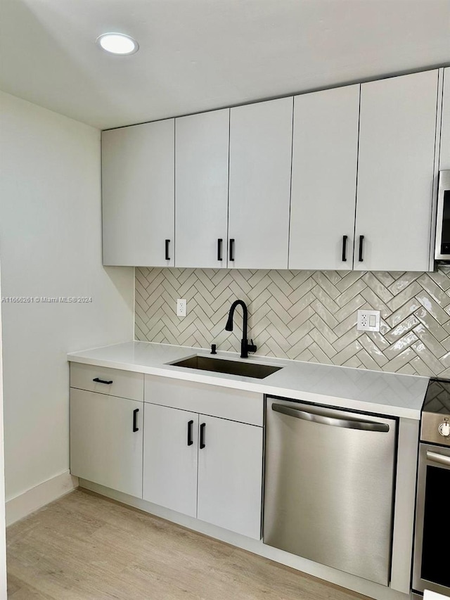 kitchen featuring white cabinets, stainless steel appliances, sink, and light hardwood / wood-style flooring