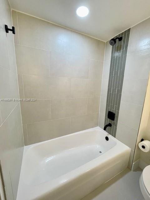 bathroom featuring tiled shower / bath combo and toilet