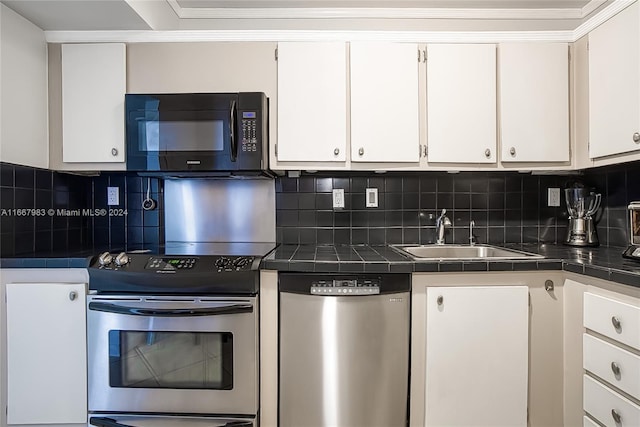 kitchen featuring white cabinets, appliances with stainless steel finishes, tasteful backsplash, and sink