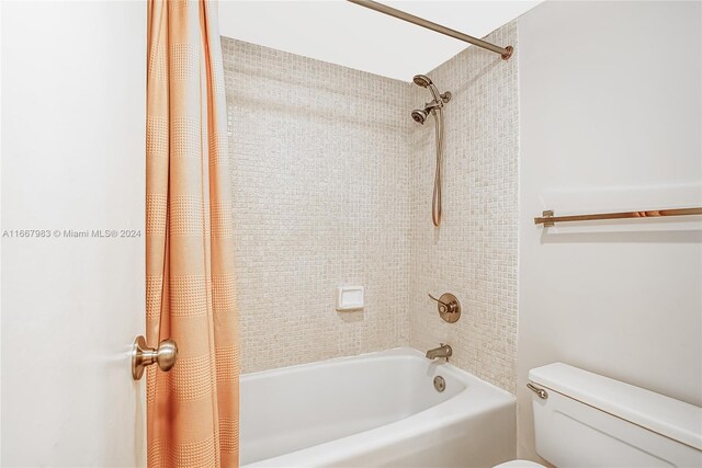 bathroom with shower / bath combo with shower curtain and toilet