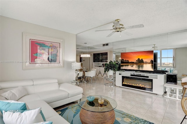 living room featuring a textured ceiling, light tile patterned floors, and ceiling fan