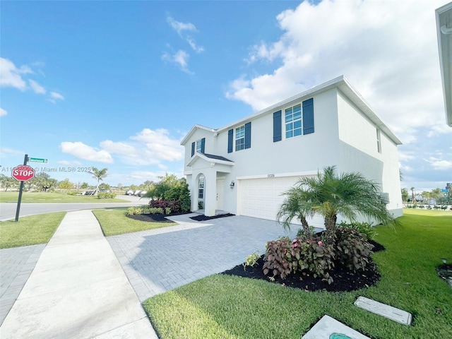 view of front of house with a front yard, decorative driveway, an attached garage, and stucco siding