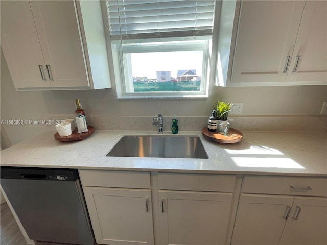 kitchen with light stone countertops, sink, white cabinetry, and stainless steel dishwasher