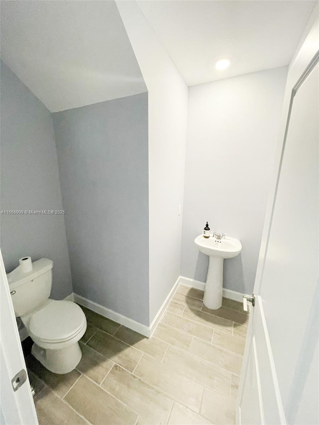 half bath featuring toilet and baseboards