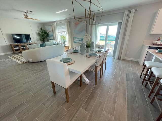 dining room featuring visible vents, ceiling fan with notable chandelier, baseboards, and wood finish floors