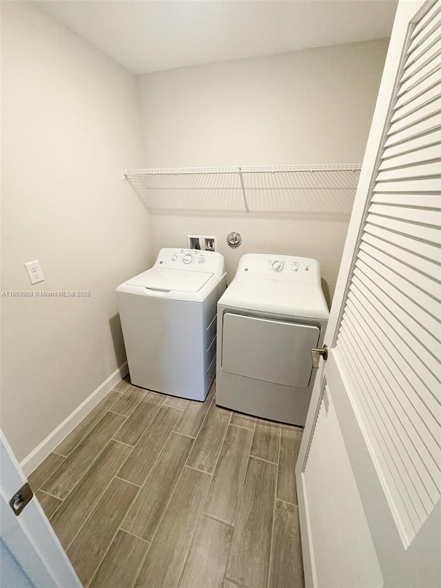 washroom featuring laundry area, baseboards, wood finish floors, and separate washer and dryer