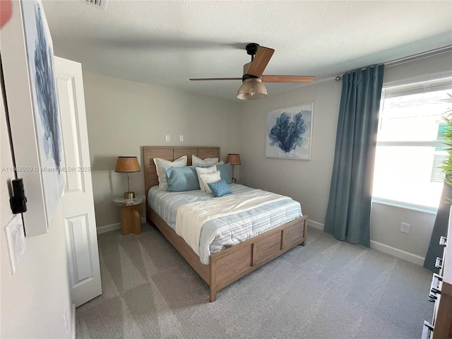 bedroom featuring baseboards, light carpet, a textured ceiling, and ceiling fan