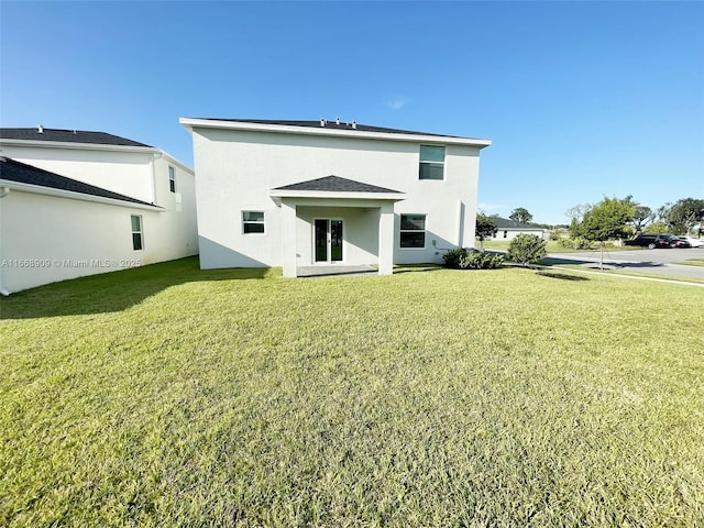 back of property featuring stucco siding, a lawn, and french doors