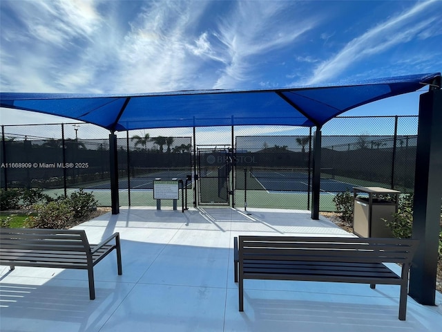 view of home's community featuring a tennis court, a gate, and fence