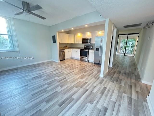 kitchen featuring light wood-type flooring, sink, white cabinets, stainless steel appliances, and ceiling fan