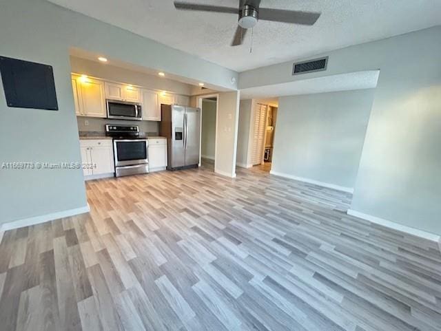 kitchen with light wood-type flooring, a textured ceiling, white cabinets, stainless steel appliances, and ceiling fan