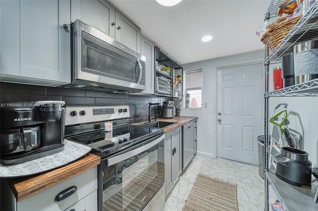 kitchen with gray cabinets, wood counters, tasteful backsplash, sink, and stainless steel appliances