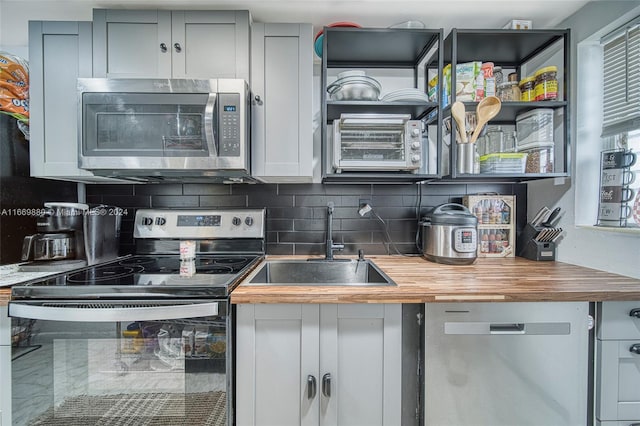 kitchen featuring sink, gray cabinetry, backsplash, appliances with stainless steel finishes, and butcher block counters