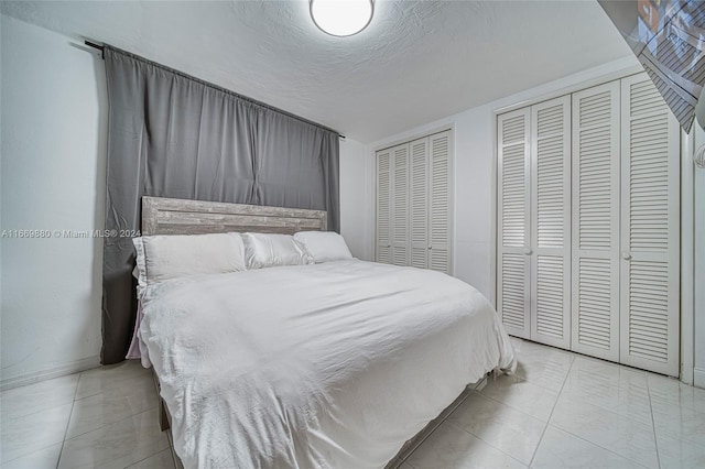 tiled bedroom featuring multiple closets and a textured ceiling