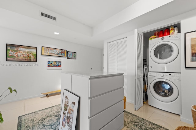 laundry room featuring stacked washer and dryer and light tile patterned floors