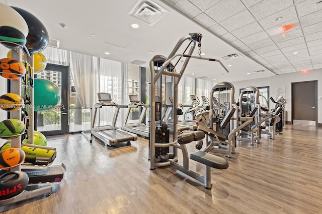 gym with a paneled ceiling and light wood-type flooring