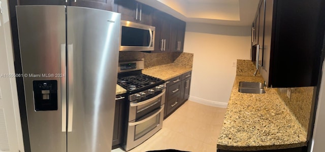 kitchen featuring appliances with stainless steel finishes, light stone countertops, sink, and tasteful backsplash