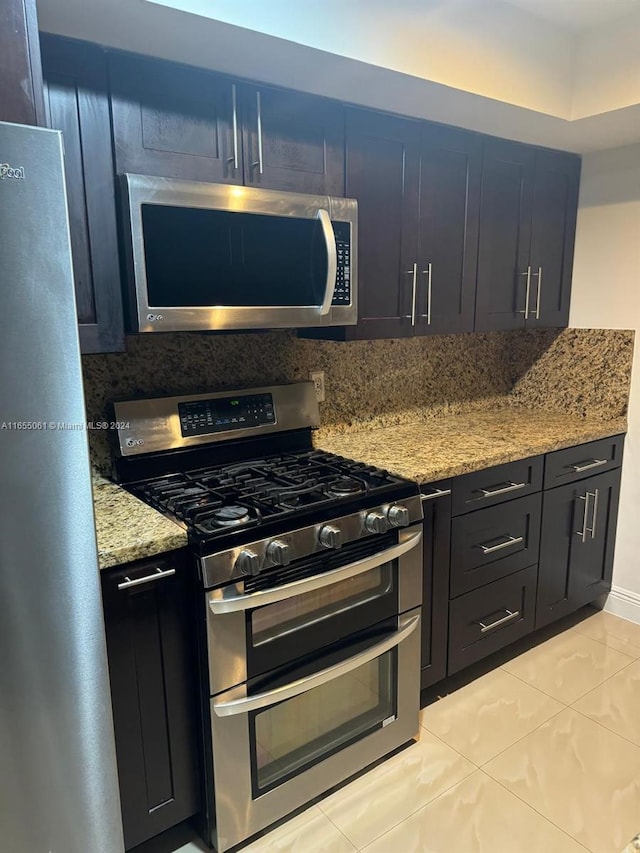 kitchen with light stone countertops, stainless steel appliances, light tile patterned floors, and decorative backsplash