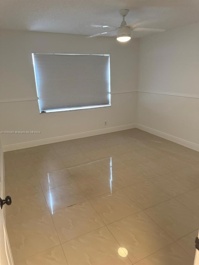 unfurnished room featuring a textured ceiling, tile patterned flooring, and ceiling fan