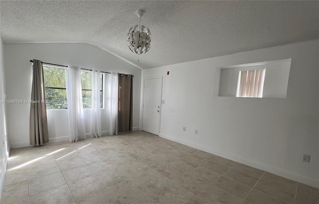 spare room featuring light tile patterned flooring, a textured ceiling, vaulted ceiling, and a chandelier