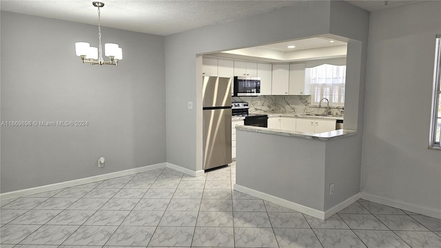 kitchen with appliances with stainless steel finishes, hanging light fixtures, white cabinets, sink, and a chandelier