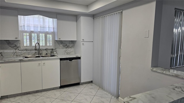 kitchen featuring tasteful backsplash, sink, white cabinetry, and stainless steel dishwasher